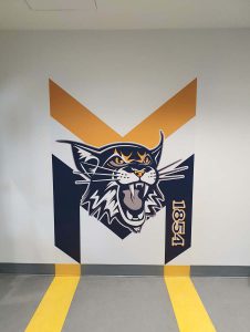 Impression du logo de l'établissement, laminage et découpe puis installation sur mur de gypse | Utilisation : Créer un sentiment d'appartenance avec le logo sur le mur